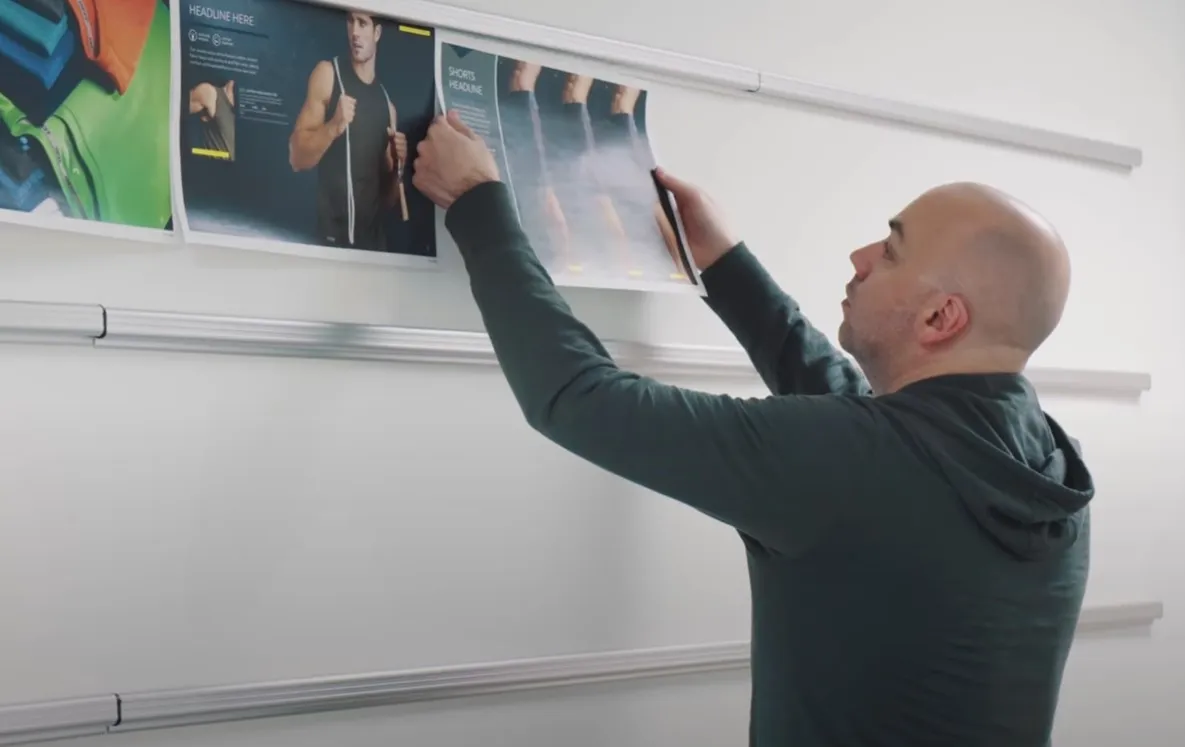 man hanging design ideas up on a design wall for evaluation
